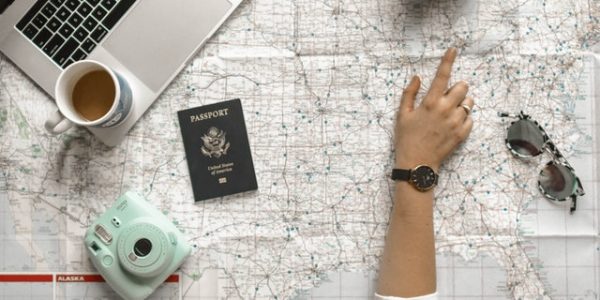electronic devices and passport over a world map used for travel planning