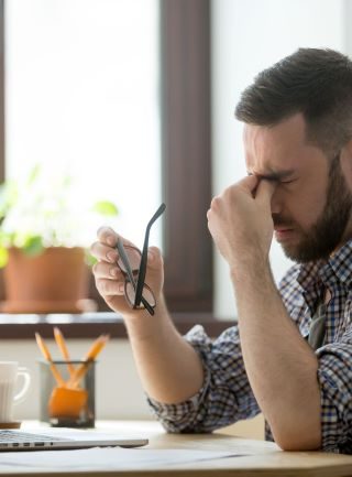 A man holding a glass looks stressed