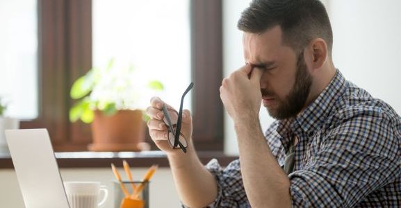 A man holding a glass looks stressed